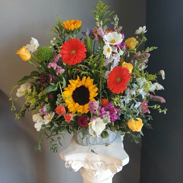 Mixed bouquet with sunflowers, gerbera daisies, and roses in a vase