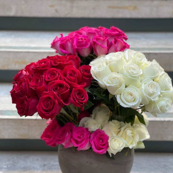 Three rose bouquets in pink, red, and white arranged in a round vase