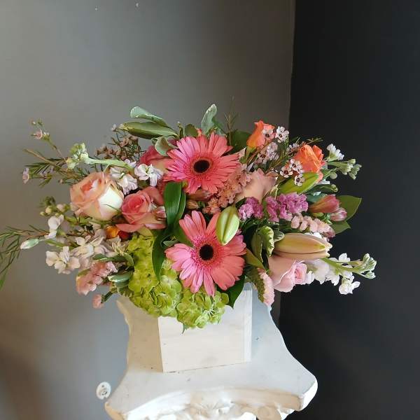 Pink gerbera daisies and roses in a white vase with mixed blooms