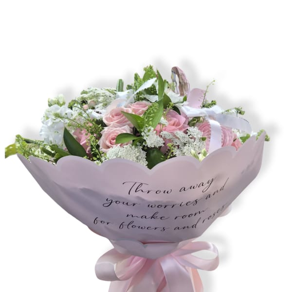 Pink rose bouquet wrapped in pale pink paper with a ribbon