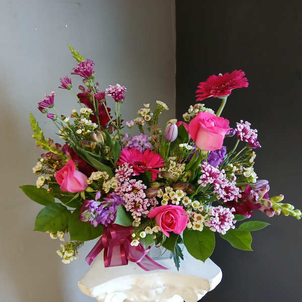 Pink and purple mixed bouquet in a clear vase with a ribbon