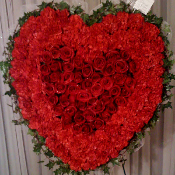 Heart-shaped red rose and carnation standing spray on an easel