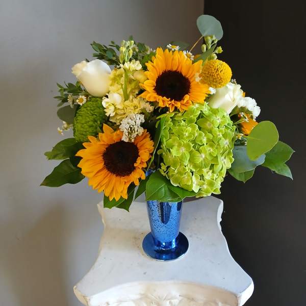 Sunflower and hydrangea bouquet in a blue vase