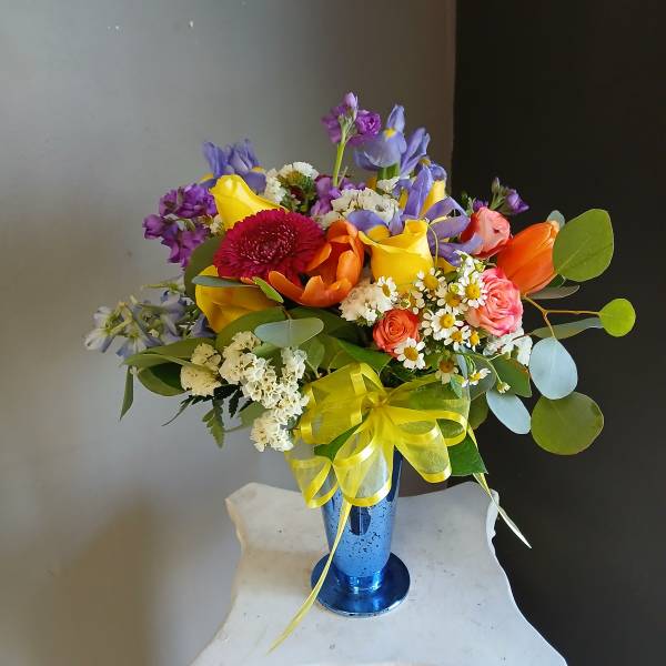 Colorful mixed bouquet in a blue vase with a yellow ribbon