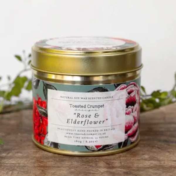 Gold tin candle with floral label on a wooden surface