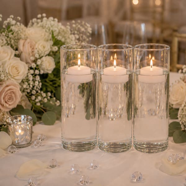 Three floating candles in glass cylinders on a floral table centerpiece