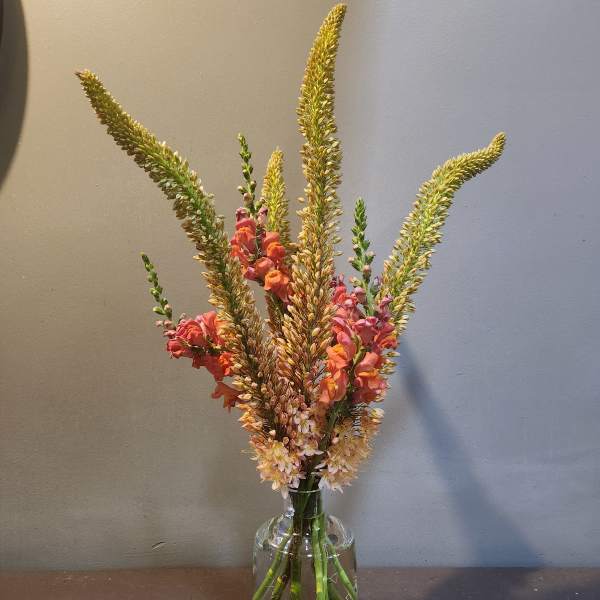 Tall mixed flower arrangement in a clear glass vase