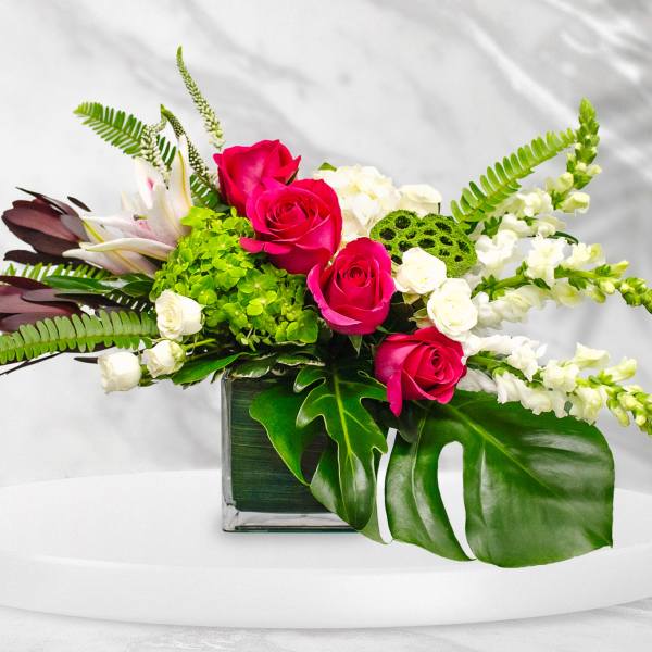 Pink roses and white flowers in a square glass vase