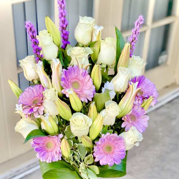 Pink gerbera daisies and white roses in a clear glass vase