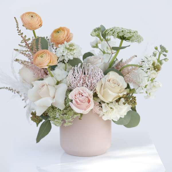 Pastel bouquet of roses and ranunculus in a blush vase