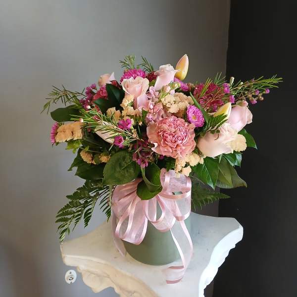 Pink and cream bouquet in a green vase with a pink ribbon