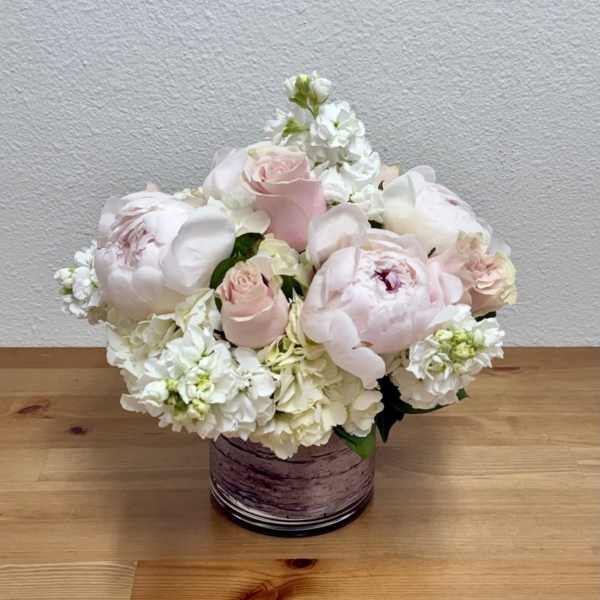 Blush pink roses and white peonies in a purple glass vase