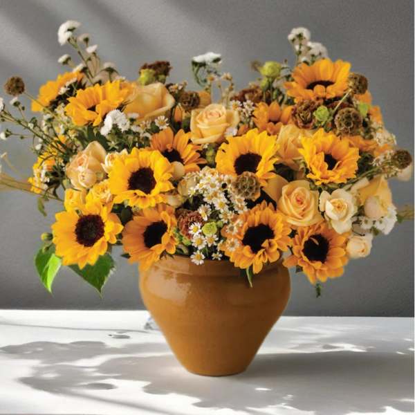 Sunflower and peach rose arrangement in a terracotta vase