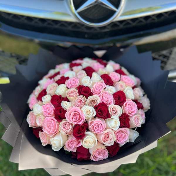 Bouquet of pink, white, and red roses wrapped in black paper