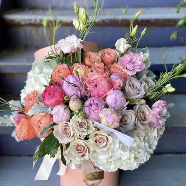 Round pink hat box of pink peonies, peach and cream roses, and white hydrangeas