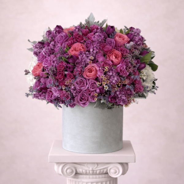 Pink and purple rose arrangement in a gray hat box