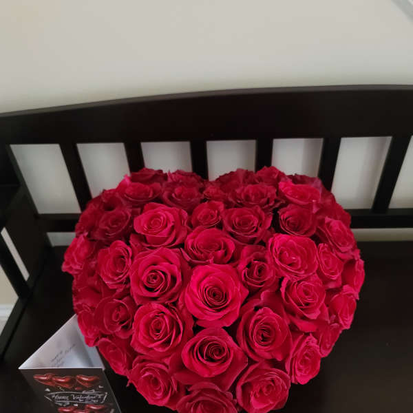 Heart-shaped bouquet of red roses on a black chair