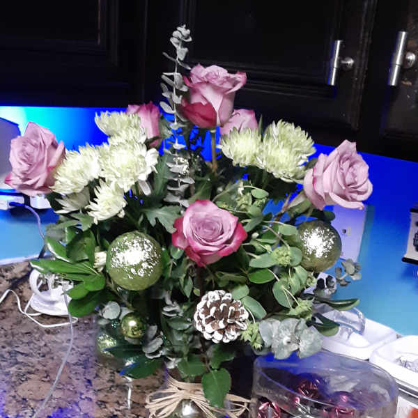 Pink roses and white chrysanthemums in a glass vase with ornaments