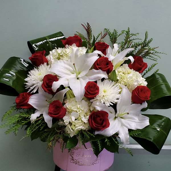 Red roses and white lilies in a pink box arrangement