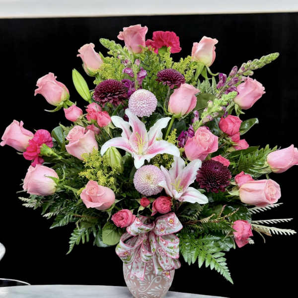 Pink roses and lilies in a decorative vase with a ribbon