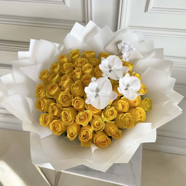 Bouquet of yellow roses with white orchids wrapped in white paper