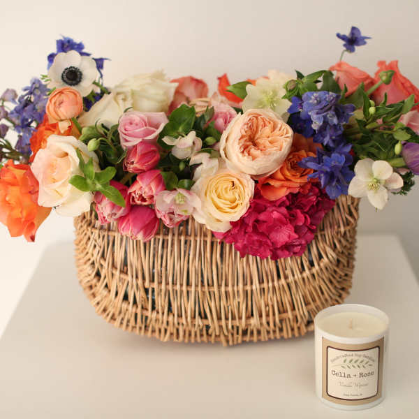 Mixed bouquet in a wicker basket with a candle beside it