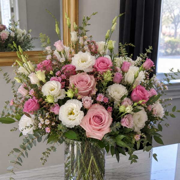 Pink and white roses with white lisianthus in a glass vase