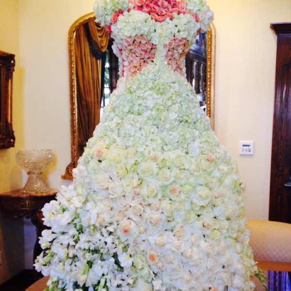 Large white and blush floral gown-shaped arrangement on a table