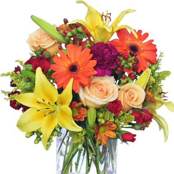 Colorful bouquet of lilies, roses, and daisies in a clear glass vase