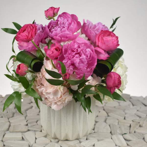 Pink peonies and roses arranged in a white vase