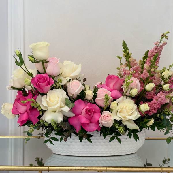 Pink and white roses with pink snapdragons in a white oval vase