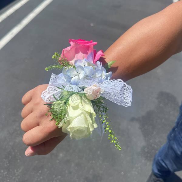 Small wrist corsage with pink and white roses and pale blue flowers