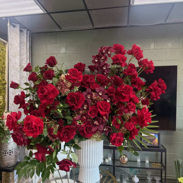 Large red rose arrangement in a white pedestal vase