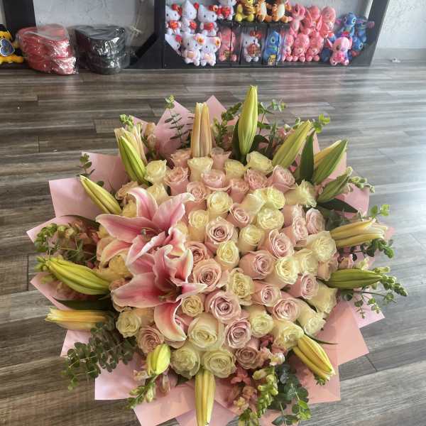 Large bouquet of pink and cream roses with pink lilies and pastel wrapping