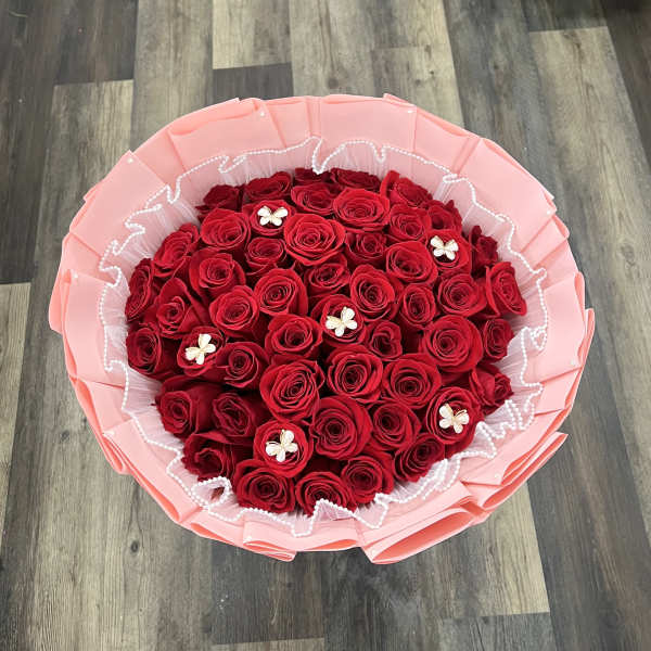 Round bouquet of red roses wrapped in pink paper