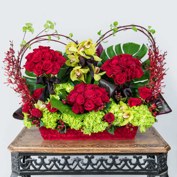 Red roses and green orchids in a decorative basket arrangement