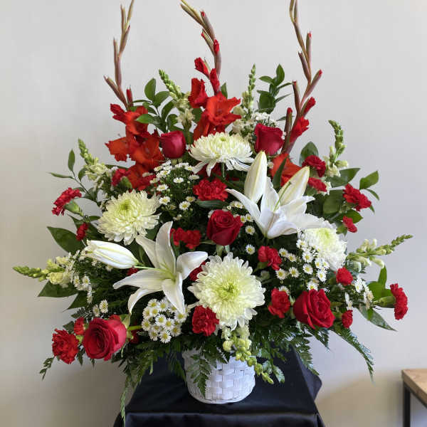 Red and white floral arrangement in a white basket vase