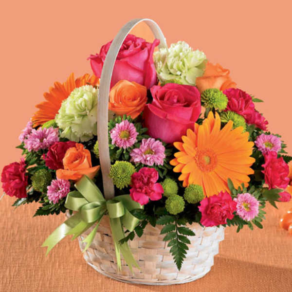 Basket arrangement of pink and orange flowers with a green ribbon