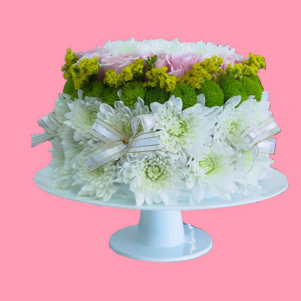 White and green floral arrangement on a pedestal stand with ribbon bows