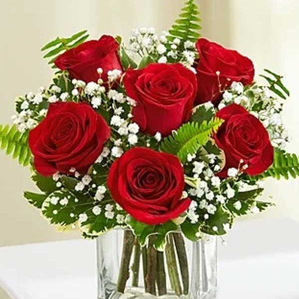 Red roses in a clear glass vase with white filler flowers