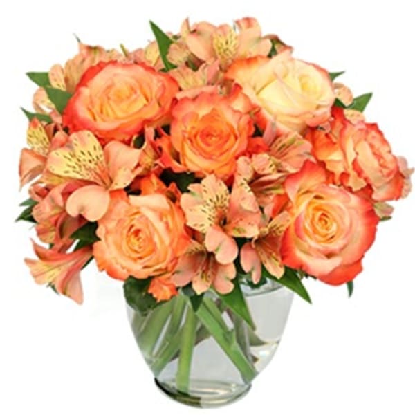 Orange roses and peach alstroemeria in a clear glass vase