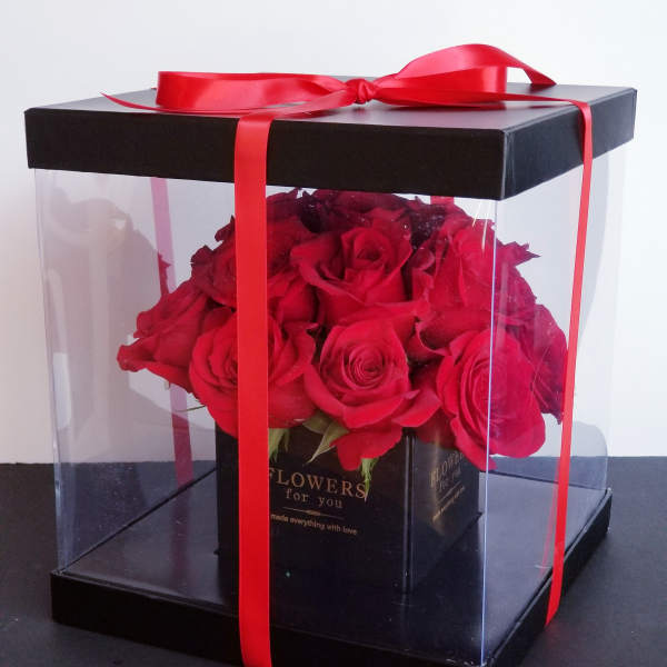 Red roses in a clear gift box tied with a red ribbon