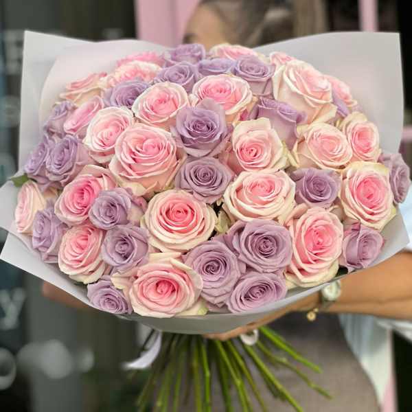 Bouquet of pink and lavender roses wrapped in white paper