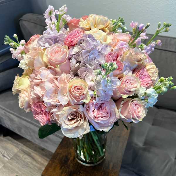Pastel bouquet of roses, hydrangeas, and stock in a glass vase