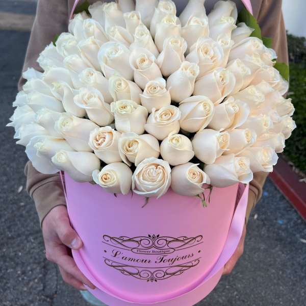 Large cluster of ivory roses arranged in a pink hat box with matching lid