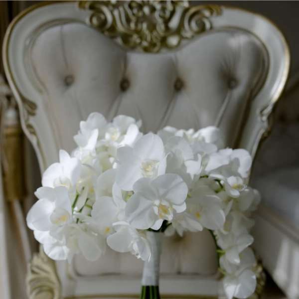 White orchid bouquet resting on an ornate chair
