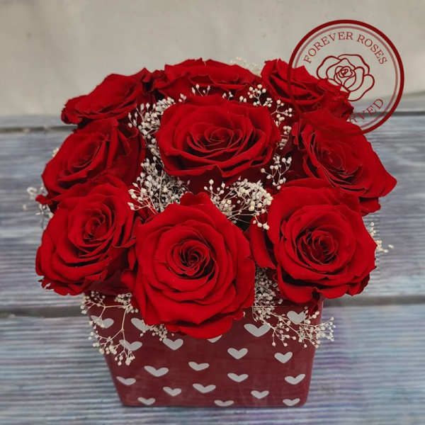 Red roses arranged in a heart-patterned box with baby's breath