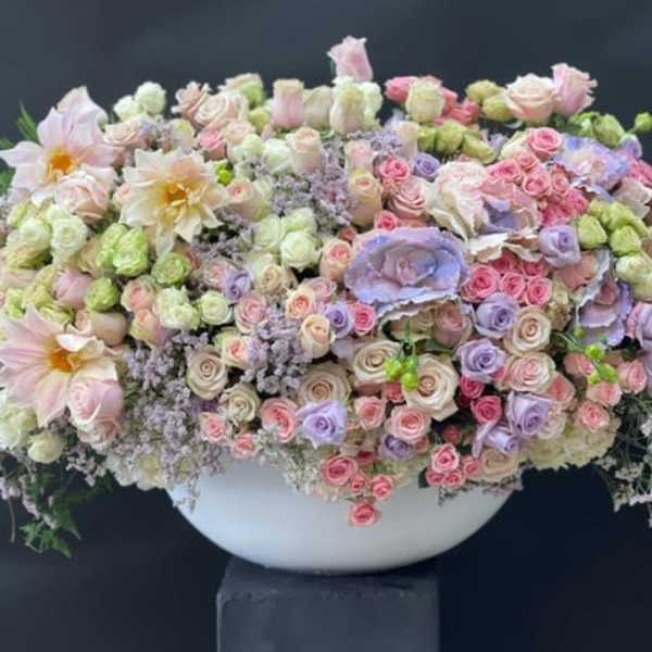 Large pastel floral arrangement in a white bowl vase