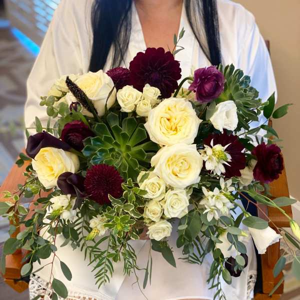 Wedding bouquet of cream and burgundy flowers with greenery