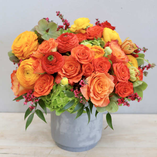 Bright orange and yellow flower arrangement in a gray vase